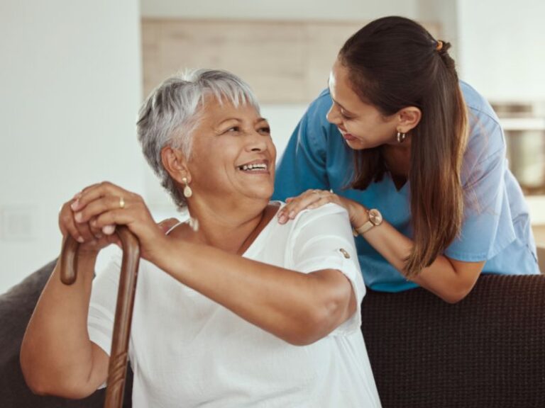 woman with a walking cane happily sitting with a nurse
