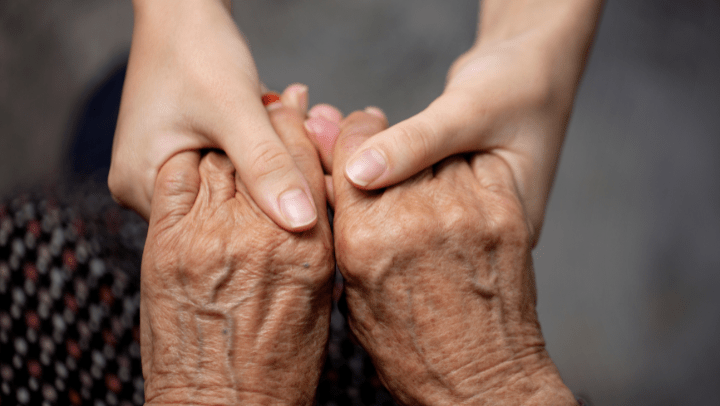 hands of a young person holding the hands of an older person 